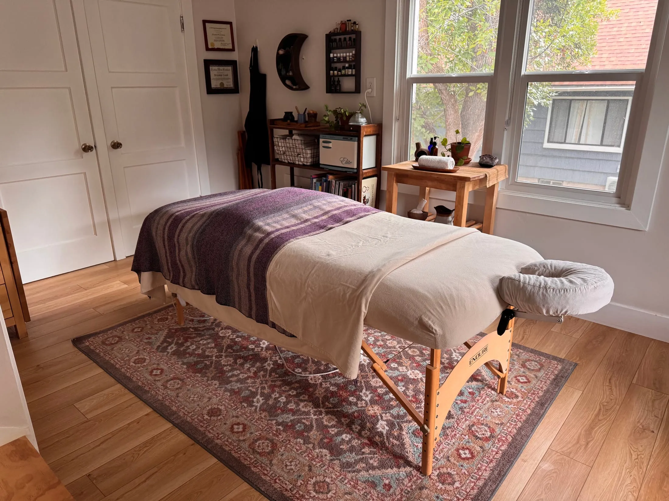 Briana's massage room: a draped table on a patterned rug beside a sunlit window